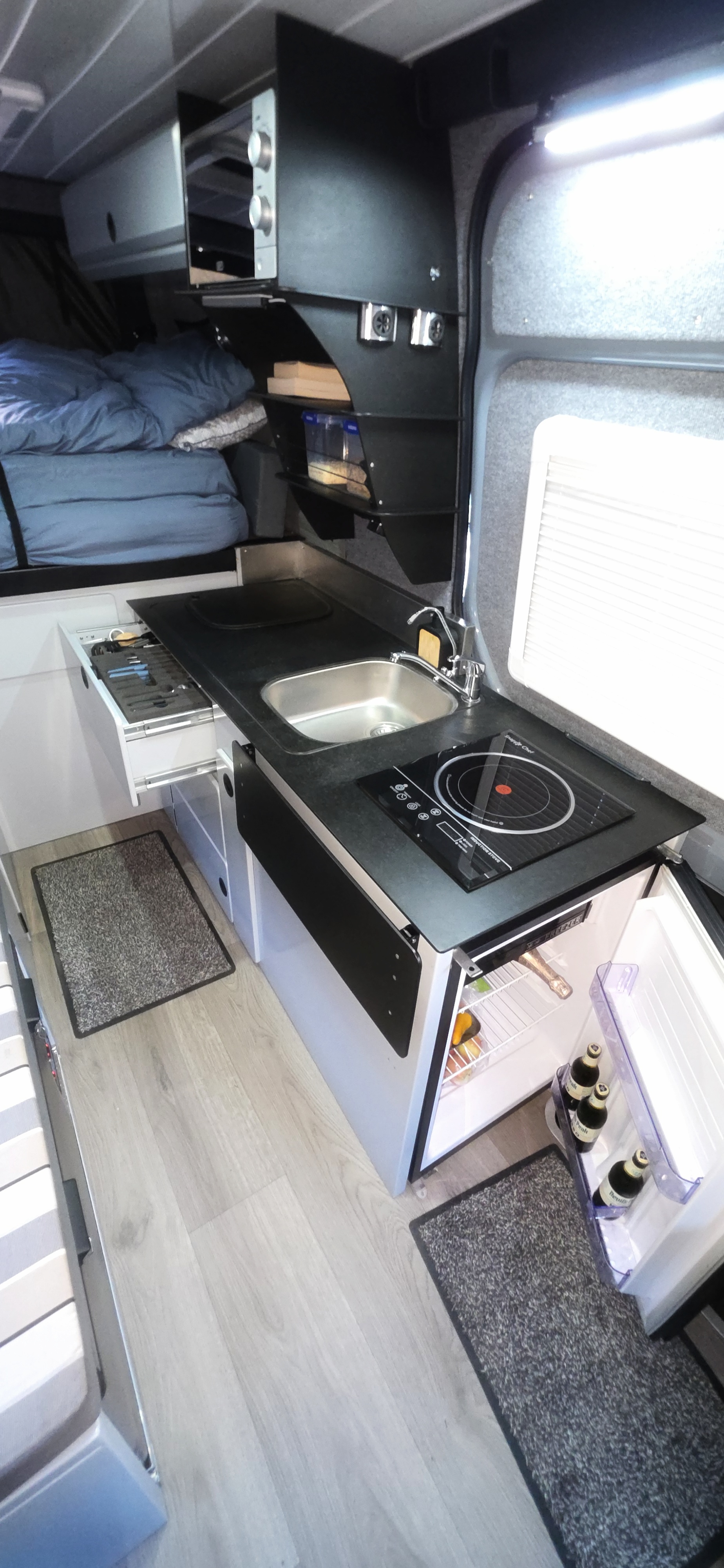 The van's fully-equipped kitchenette with an induction stove and fridge.